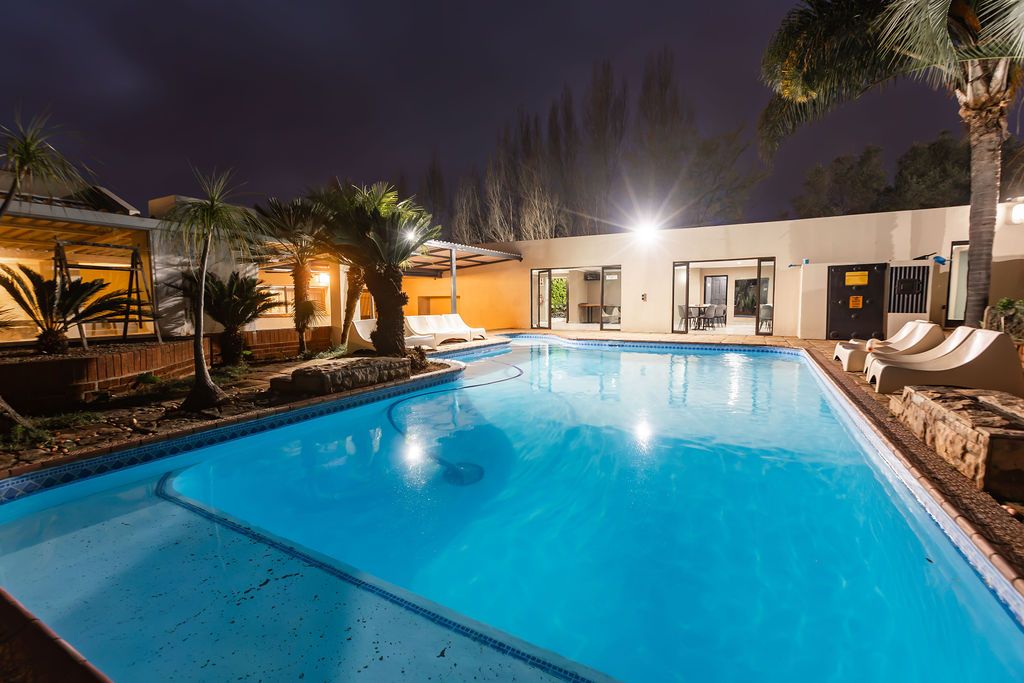 Pool and loungers at dusk with warm patio lighting